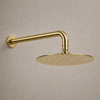 Gold shower head with arm mounted on a beige wall