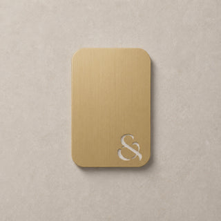 brass metallic swatch colour with ampersand design on a beige surface