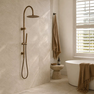 Antique brass gooseneck rain shower head and hose set in a modern bathroom with beige tiles and a free standing bath
