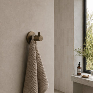 antique brass towel coat hook in a modern bathroom with beige tiles