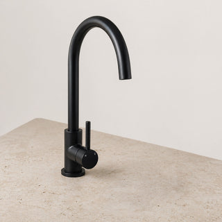 Black kitchen tap on a beige countertop with a light gray background