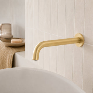brushed brass bathroom wall tap in a modern bathroom with a free standing bath and beige wall tiles