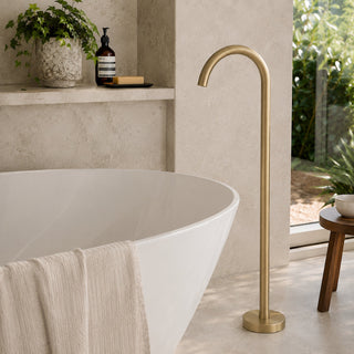 brushed brass free standing bath tap in a modern bathroom with beige tiles and a free standing bath.