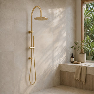 brushed brass gooseneck rain head shower set in a modern bathroom with beige tiles and a plant