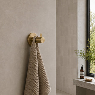 brushed brass towel coat hook in a modern bathroom with beige tiles
