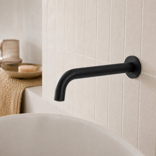 matt black bathroom wall tap in a modern bathroom with beige tiles and a free standing bath