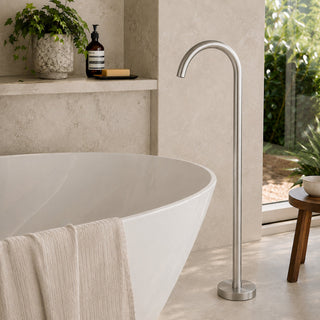nickel free standing bath tap spout in a modern bathroom with beige tiles and a free standing bath