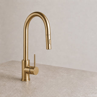 Gold kitchen tap on a beige countertop with a neutral background