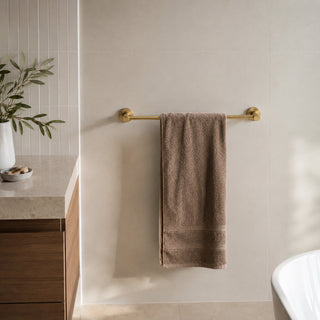 polished gold single towel rail in a modern bathroom with timber vanity and white tiles