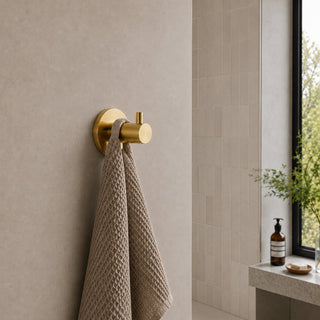 polished gold towel hook in a modern bathroom with beige tiles